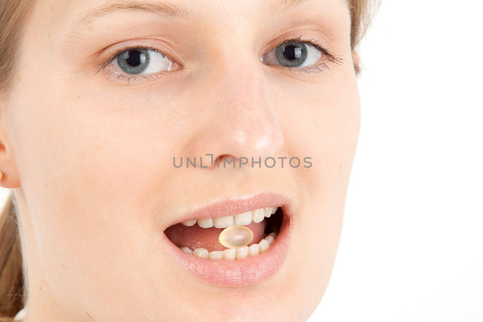 Young woman with a pill between her teeth