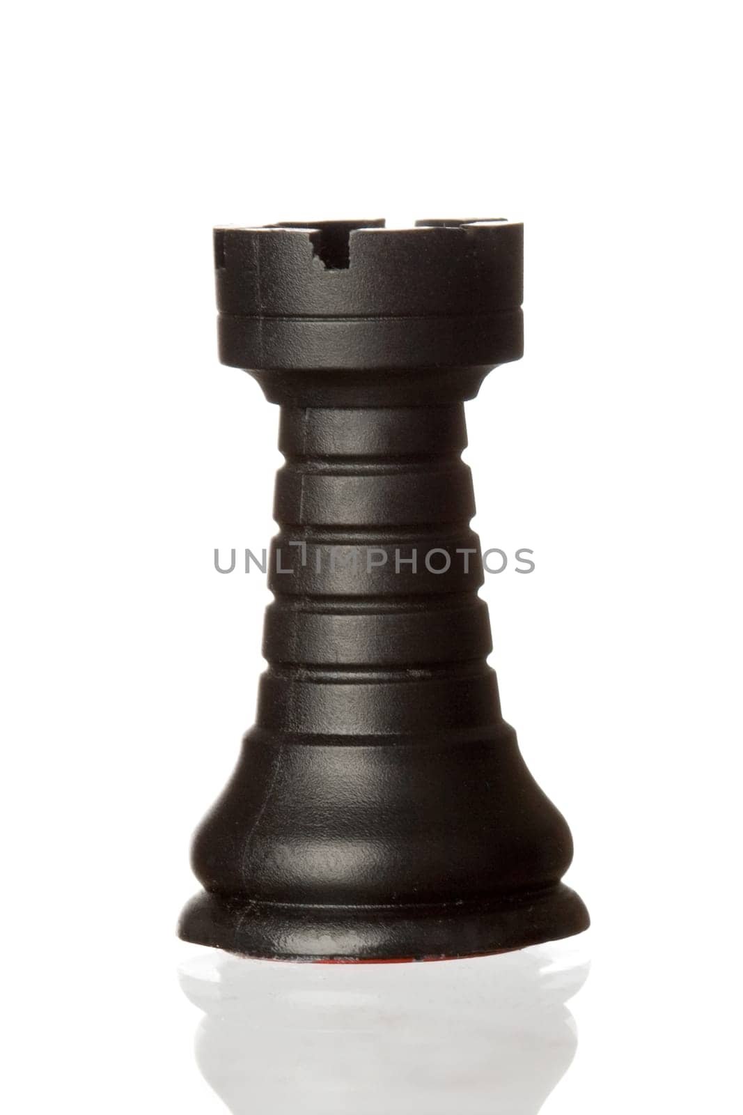 Black rook chess piece isolated on white background with reflection on the floor