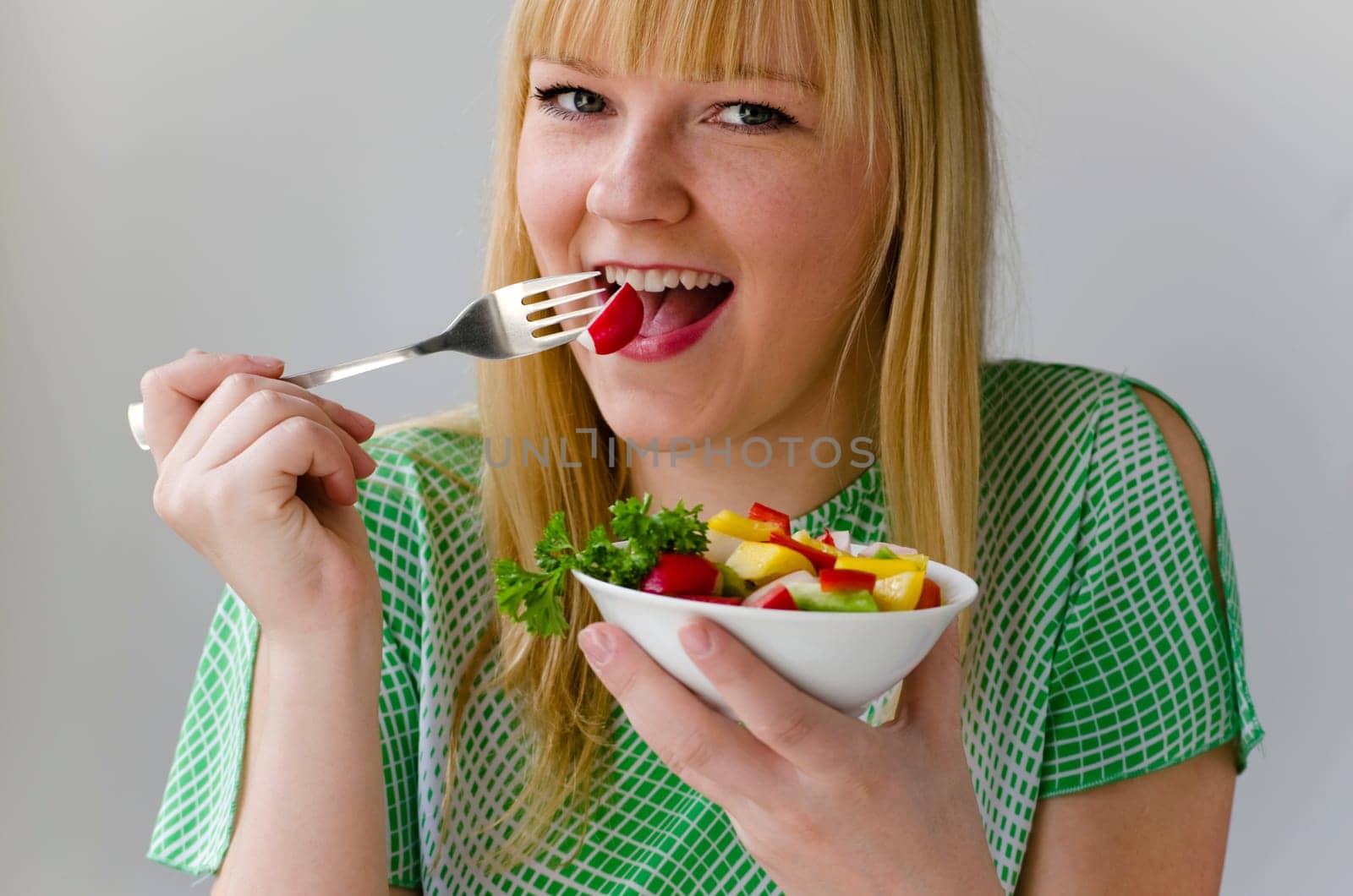 Young attractive woman eating vegetable salad