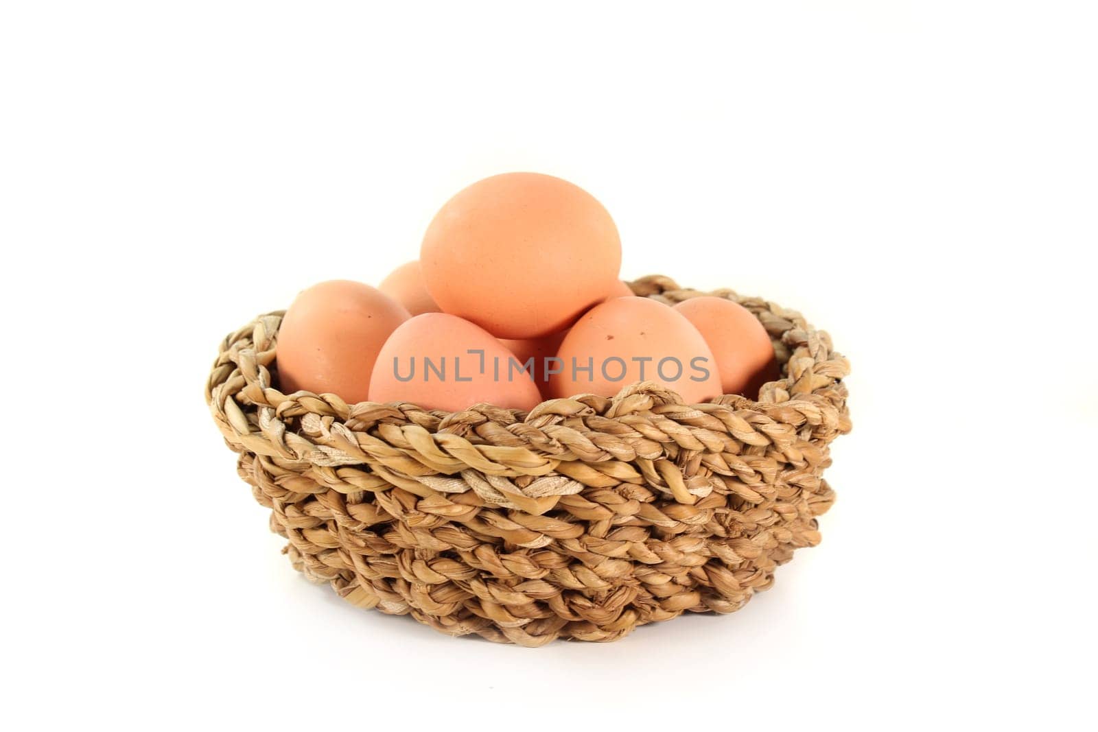 fresh raw eggs in a basket against white background