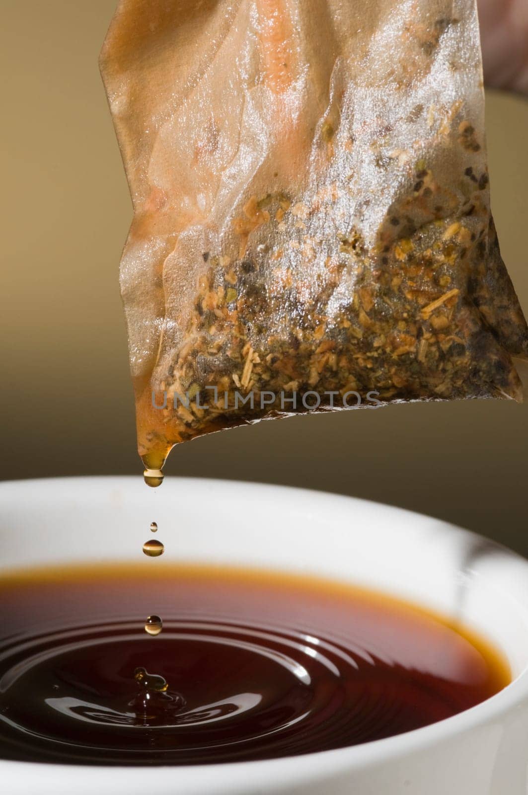 Close-up of a teacup with tea bags hanging and dripping over it