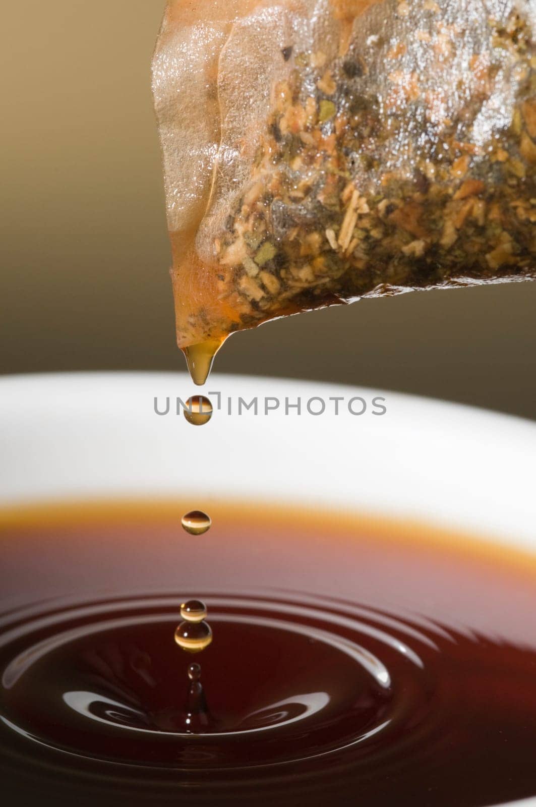 Close-up of a teacup with tea bags hanging and dripping over it