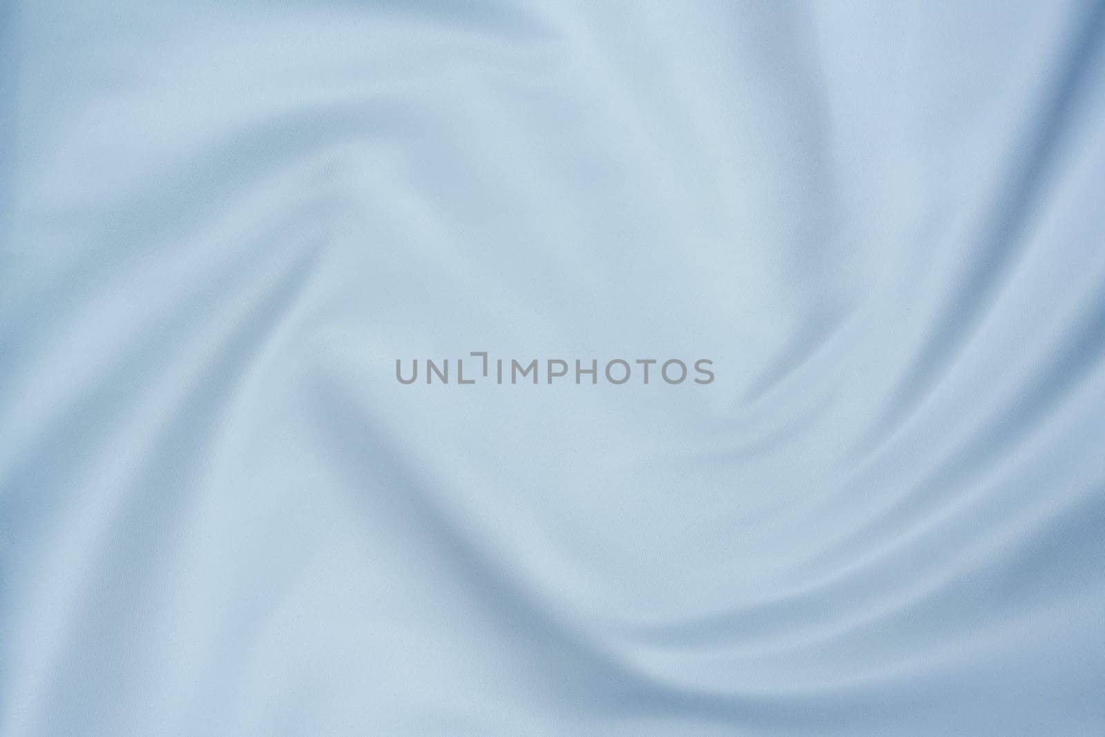 Close-up of soft white fabric with gentle folds creating a swirl pattern, perfect for backgrounds, textures, and design projects.