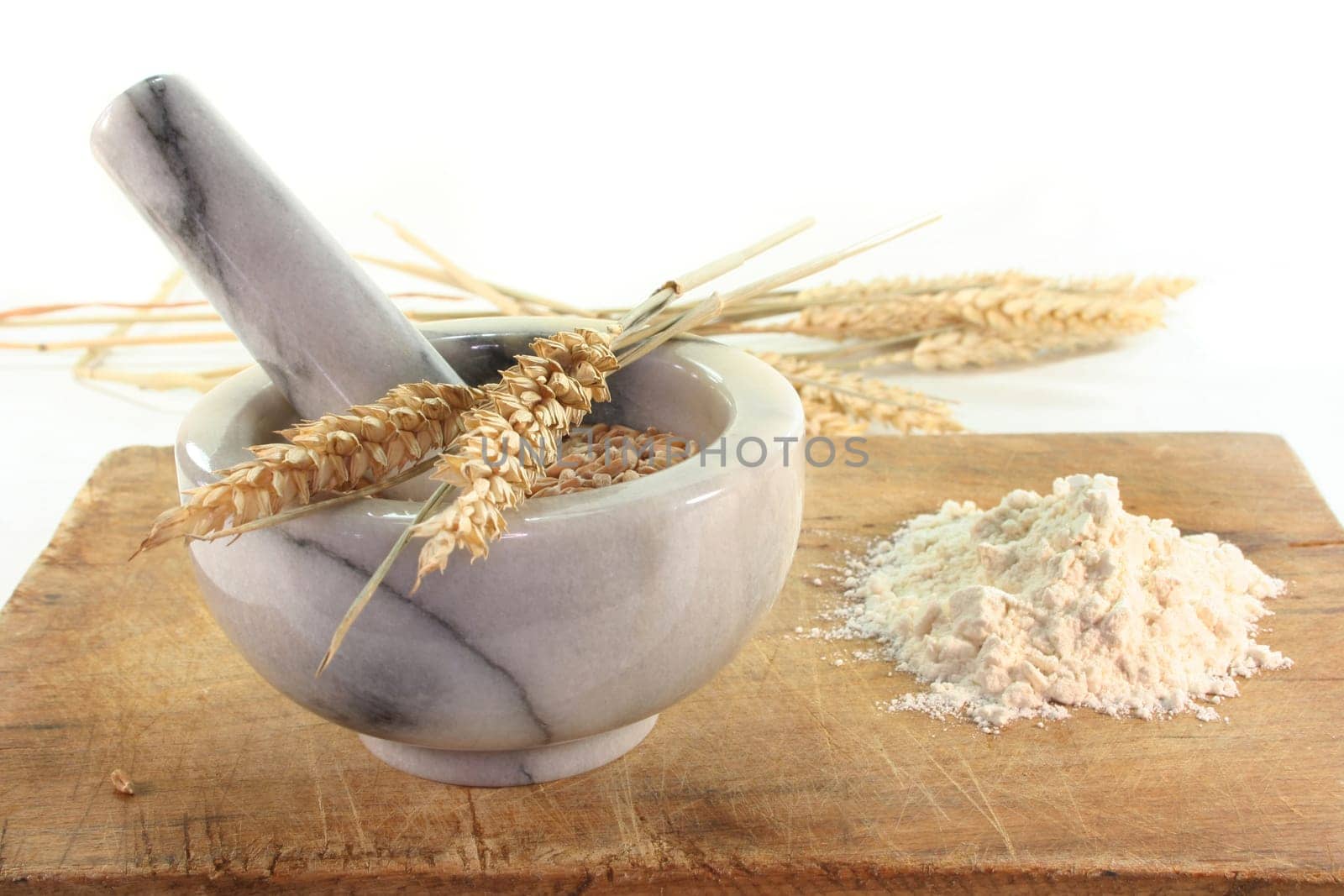 Grain in a mortar and ears of corn on a wooden board