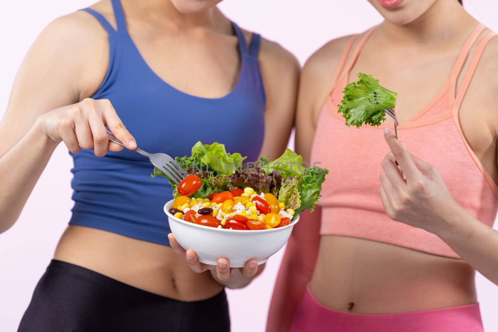 Asian woman in sportswear holding salad bowl on isolated background. Vigorous by biancoblue