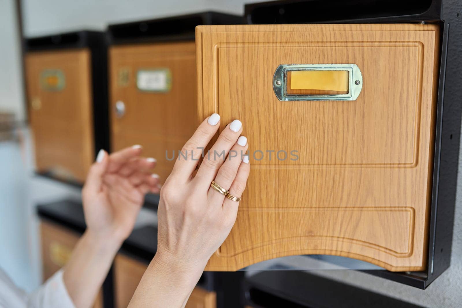 Woman checking mailboxes inside an apartment building. Postal correspondence concept