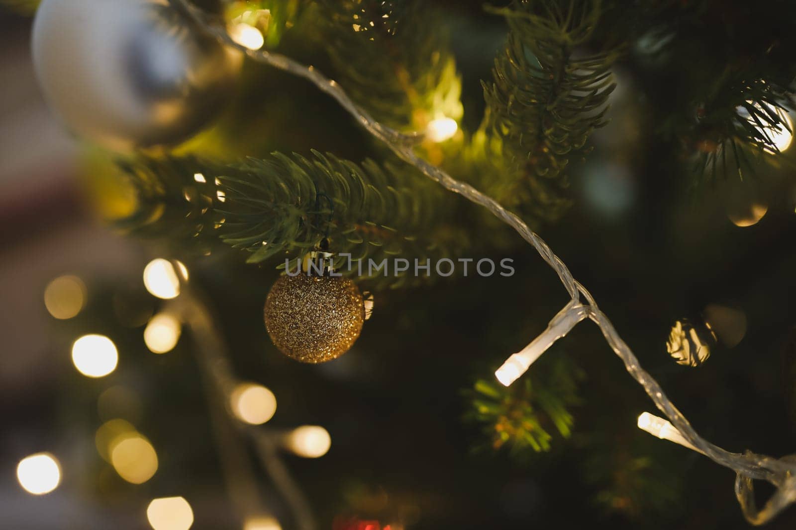 Christmas and New years eve Background. Close up of balls on christmas tree. Bokeh garlands in the background. New Year concept. Decorated Christmas tree on blurred, sparkling and fairy background