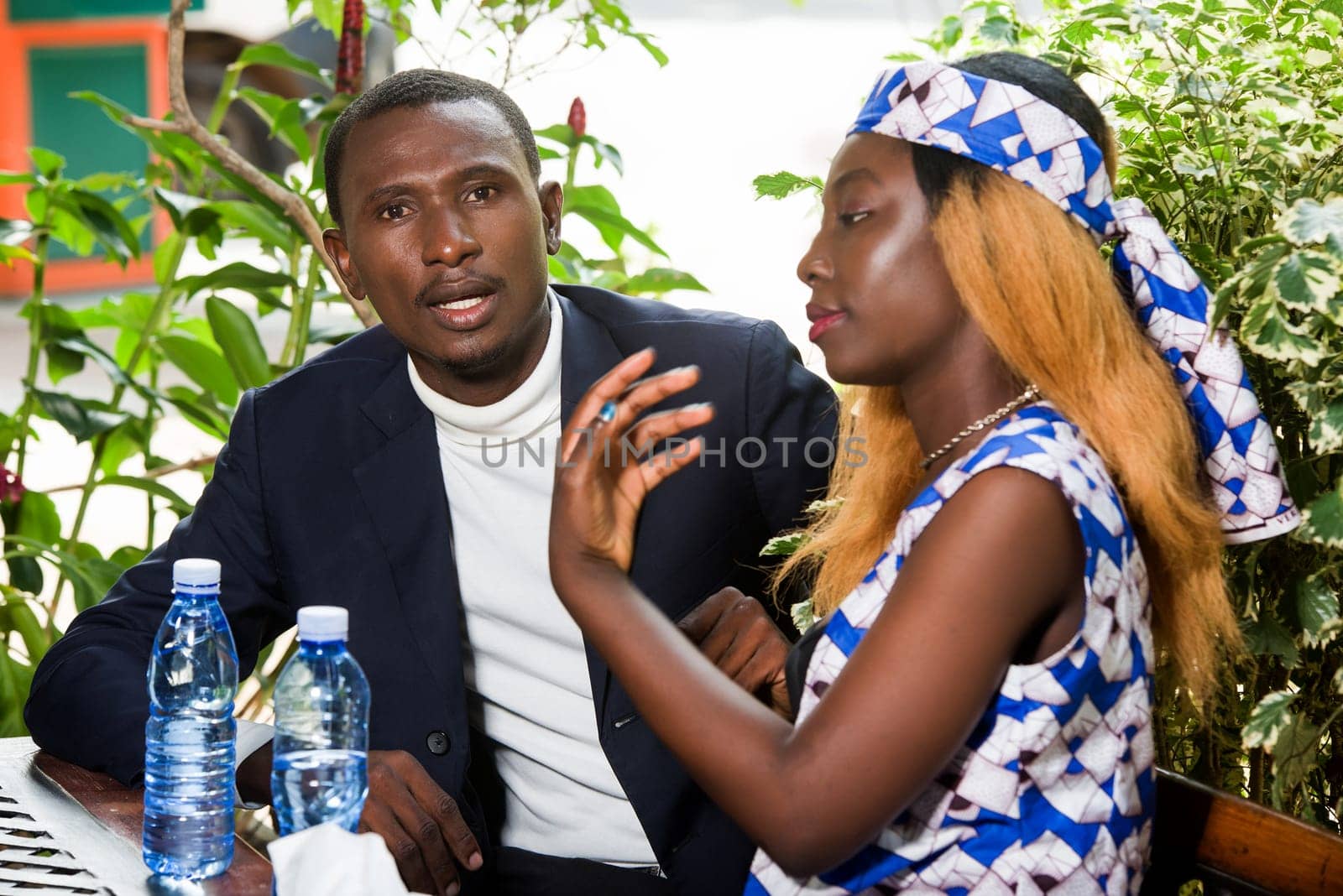 new business team man and woman sitting in office lobby during the day discussing new business ideas. Young man and woman drinking water drinking happy during a meeting.