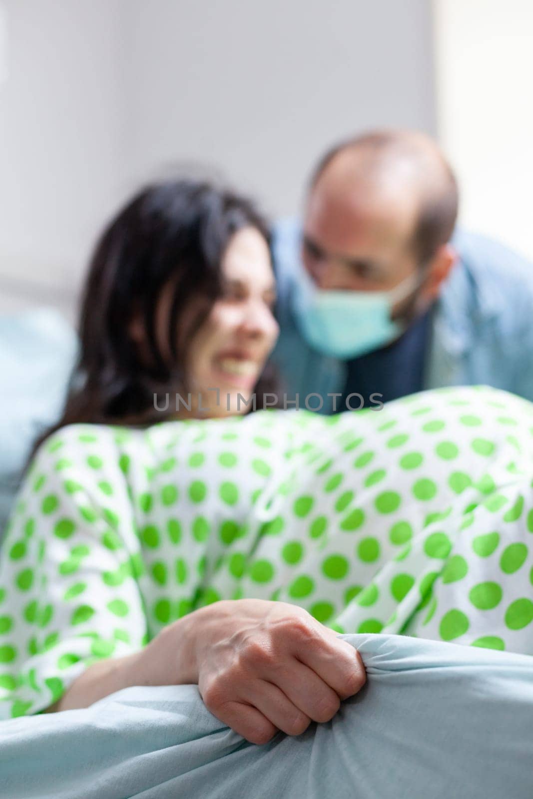 Husband comforting pregnant woman during child birth in hospital ward, future mother screaming and pushing during caesarean surgery. Patient with pregnancy getting into labor in maternity clinic