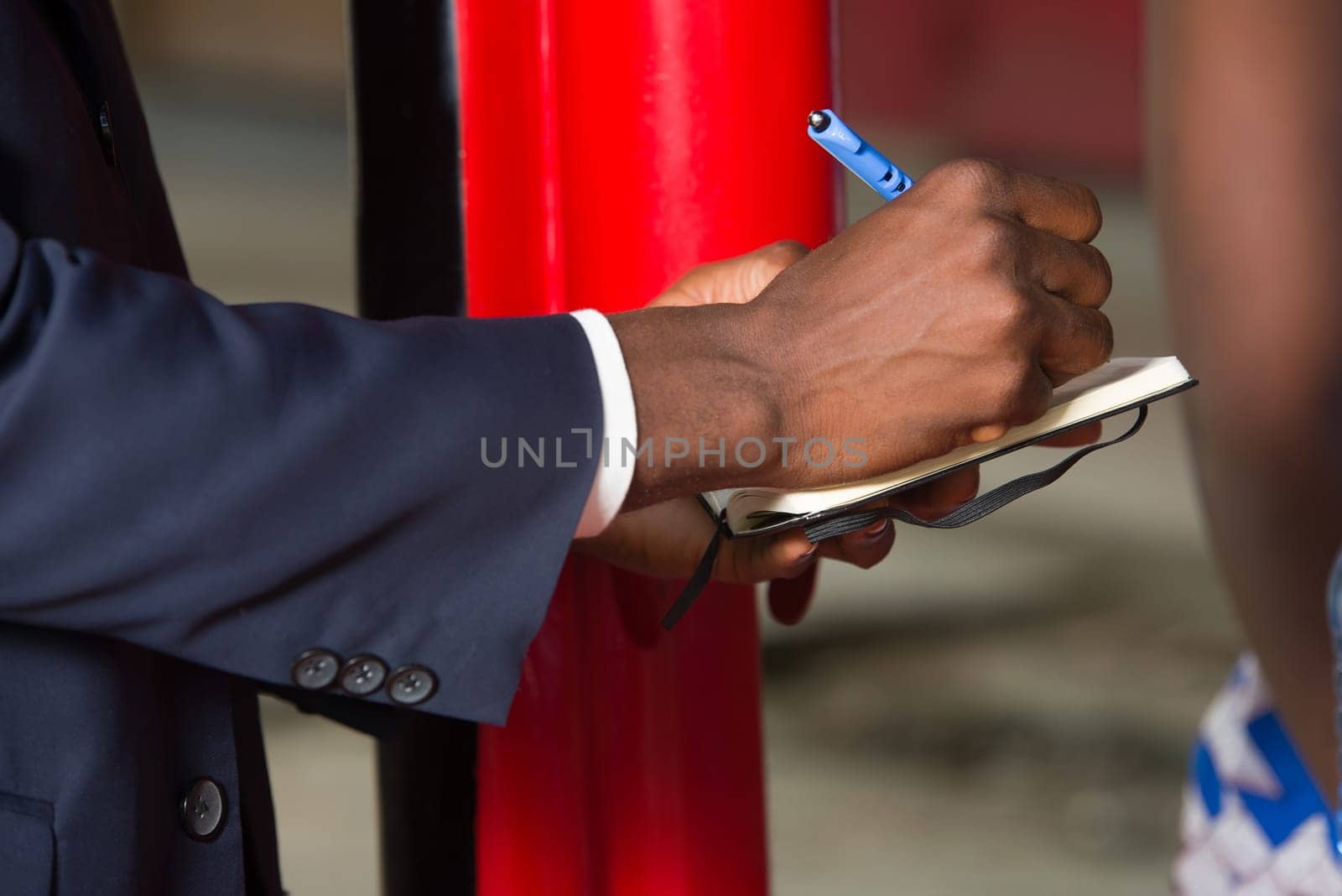 a food controller standing in a suit writing on a note pad.