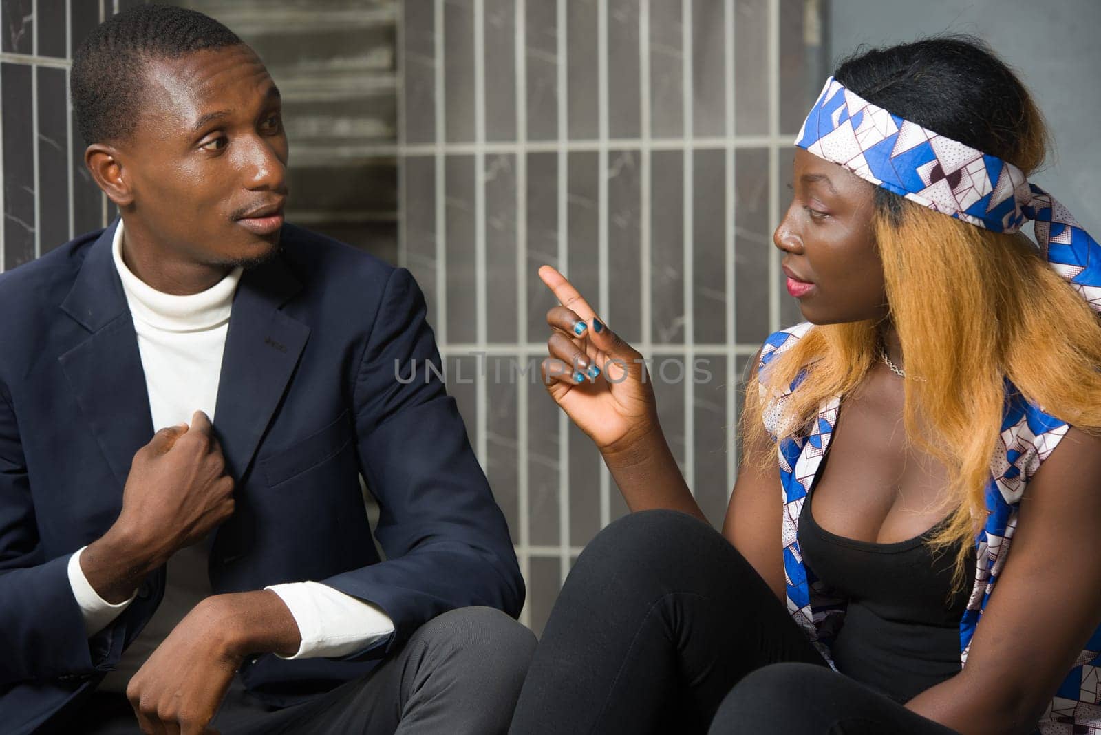 happy couple talking sitting on stairs while laughing and gesturing and looking at each other outdoors.