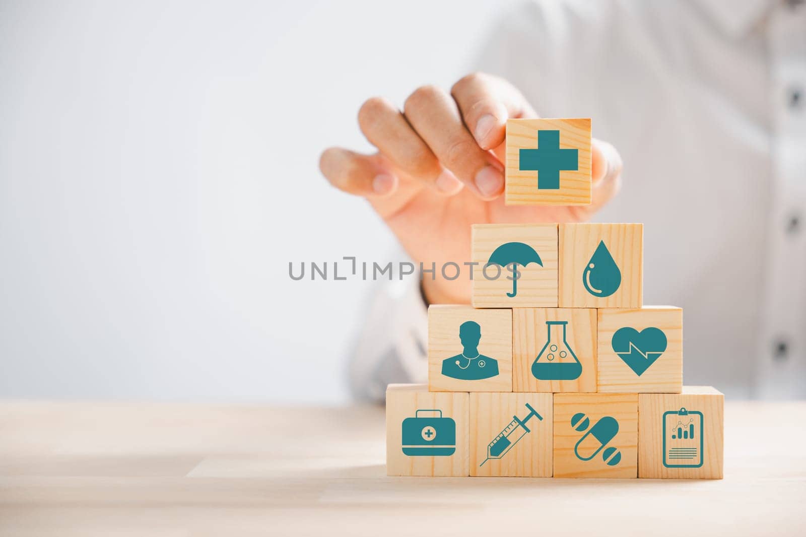 Wooden block held by hand, displaying healthcare and medical icons. Evoking safety and well-being, encompassing pharmacy, family health, and heart care. A concept of happiness. health care concept