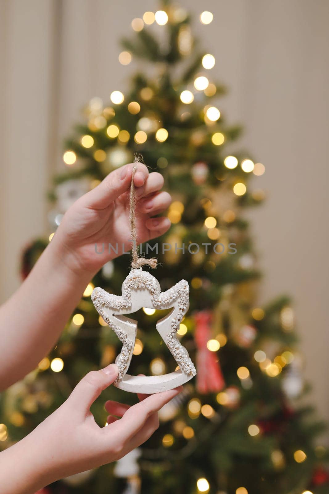 Decorating Christmas tree, holding Christmas toy in a hand. Holiday, Christmas and New Year family celebration concept.