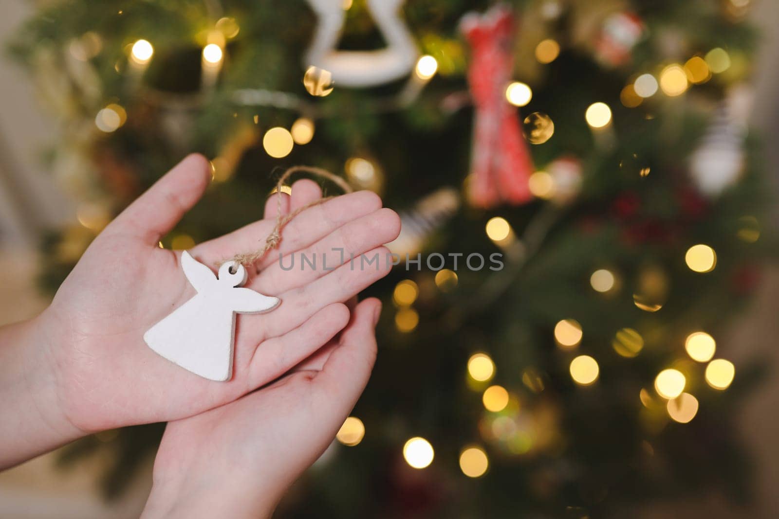 Decorating Christmas tree, holding Christmas toy in a hand. Holiday, Christmas and New Year family celebration concept.