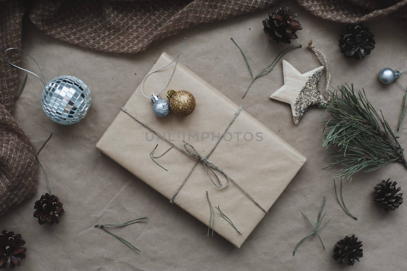 Christmas composition. Gift, fir tree branches, balls on craft paper background. Christmas, winter, new year concept. Flat lay, top view, copy space.