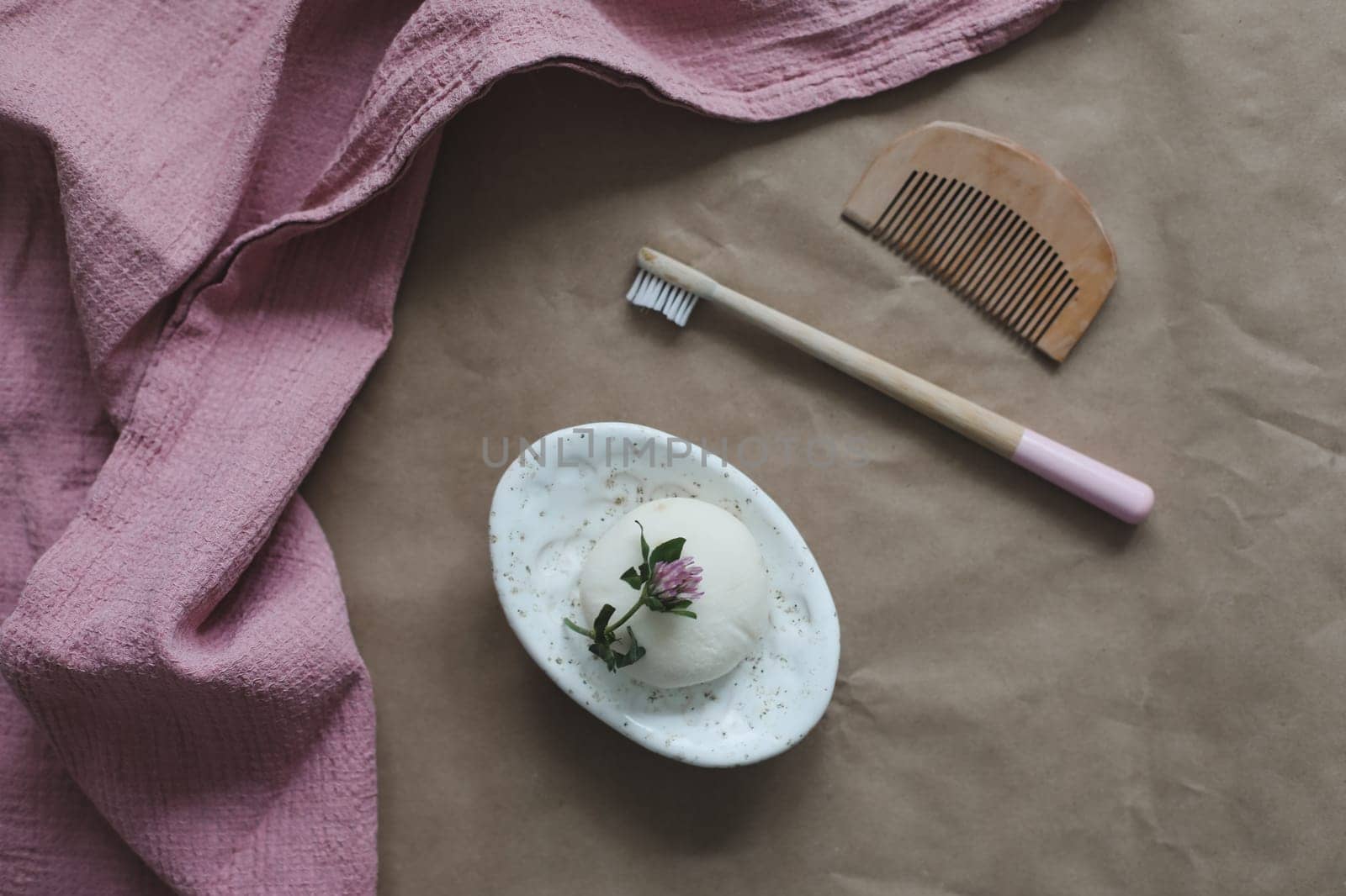 Soap bar or solid shampoo on a soap dish, bamboo toothbrush and towel top view with copyspace. Accessories for personal hygiene. Plastic free and eco friendly products in household.