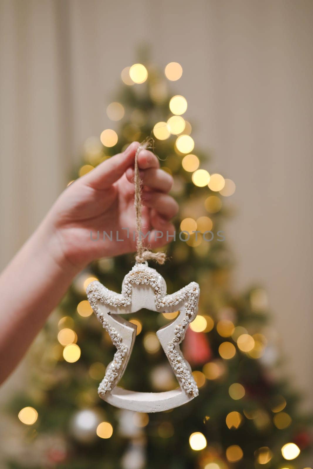 Decorating Christmas tree, holding Christmas toy in a hand. Holiday, Christmas and New Year family celebration concept.