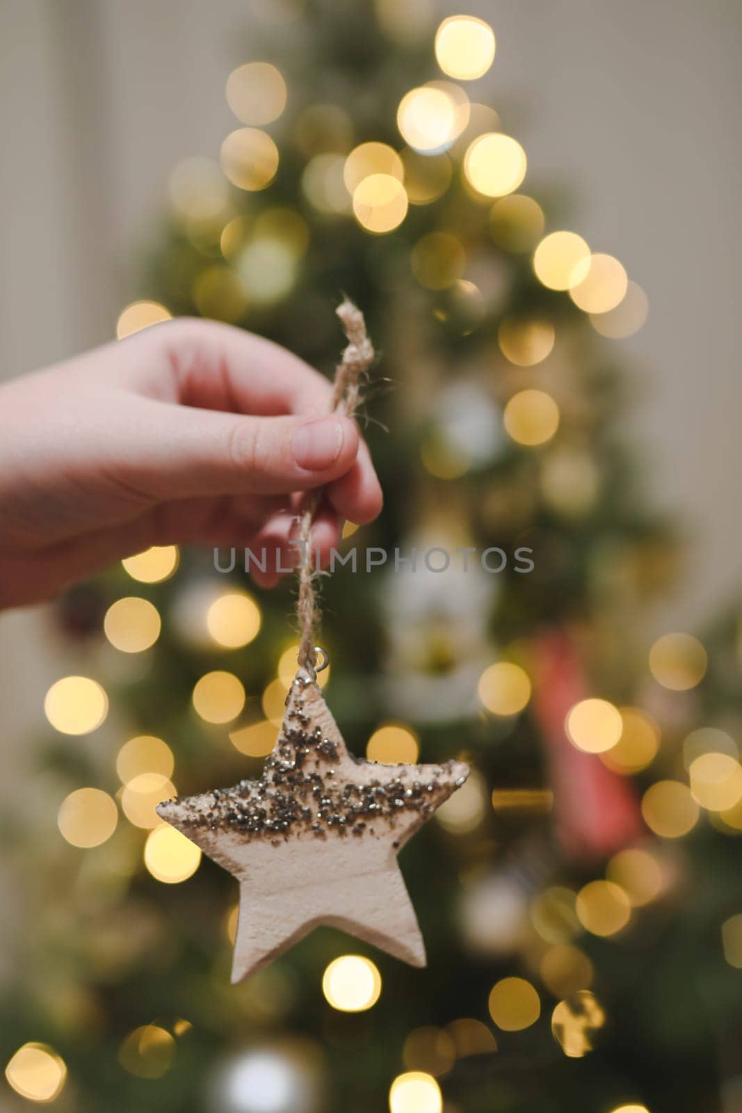Decorating Christmas tree, holding Christmas toy in a hand. Holiday, Christmas and New Year family celebration concept.