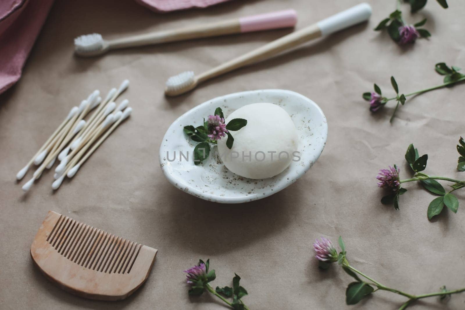 Soap bar or solid shampoo on a soap dish, bamboo toothbrush and towel top view with copyspace. Accessories for personal hygiene. Plastic free and eco friendly products in household by paralisart