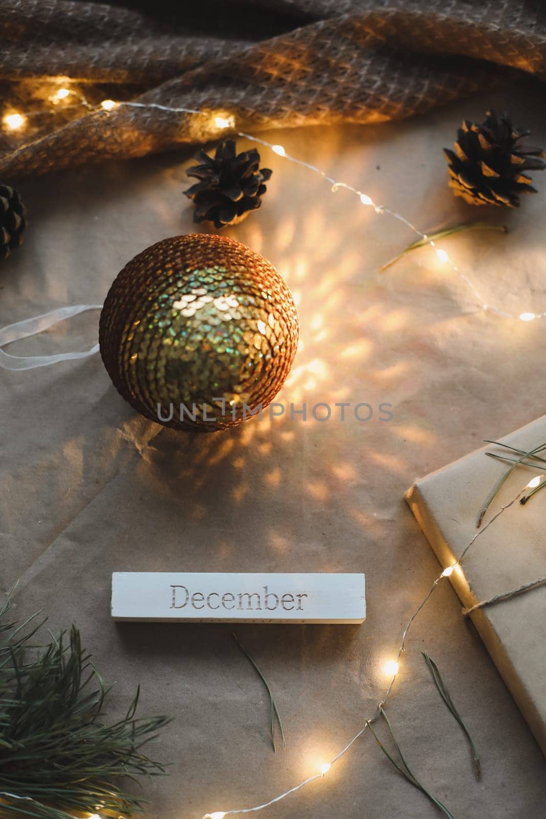 Word December on calendar by background with spruce branches and a glowing garland. Christmas, winter, new year concept by paralisart