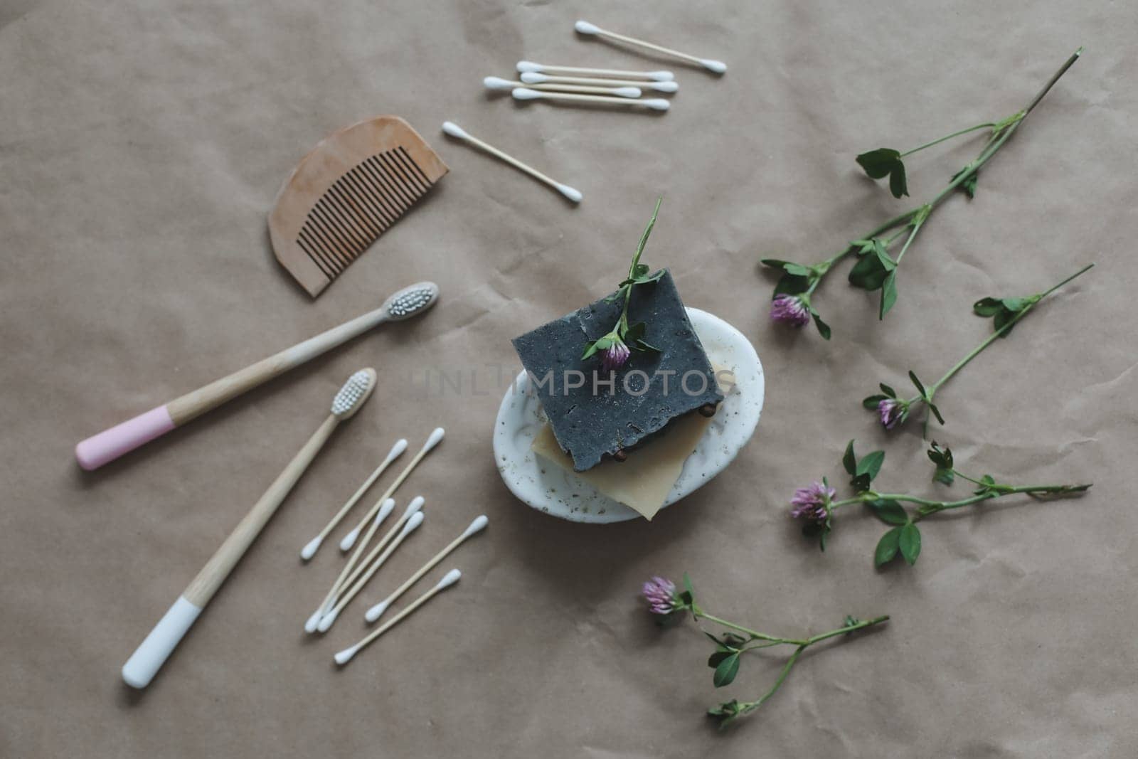 Soap bar or solid shampoo on a soap dish, bamboo toothbrush and towel top view with copyspace. Accessories for personal hygiene. Plastic free and eco friendly products in household.