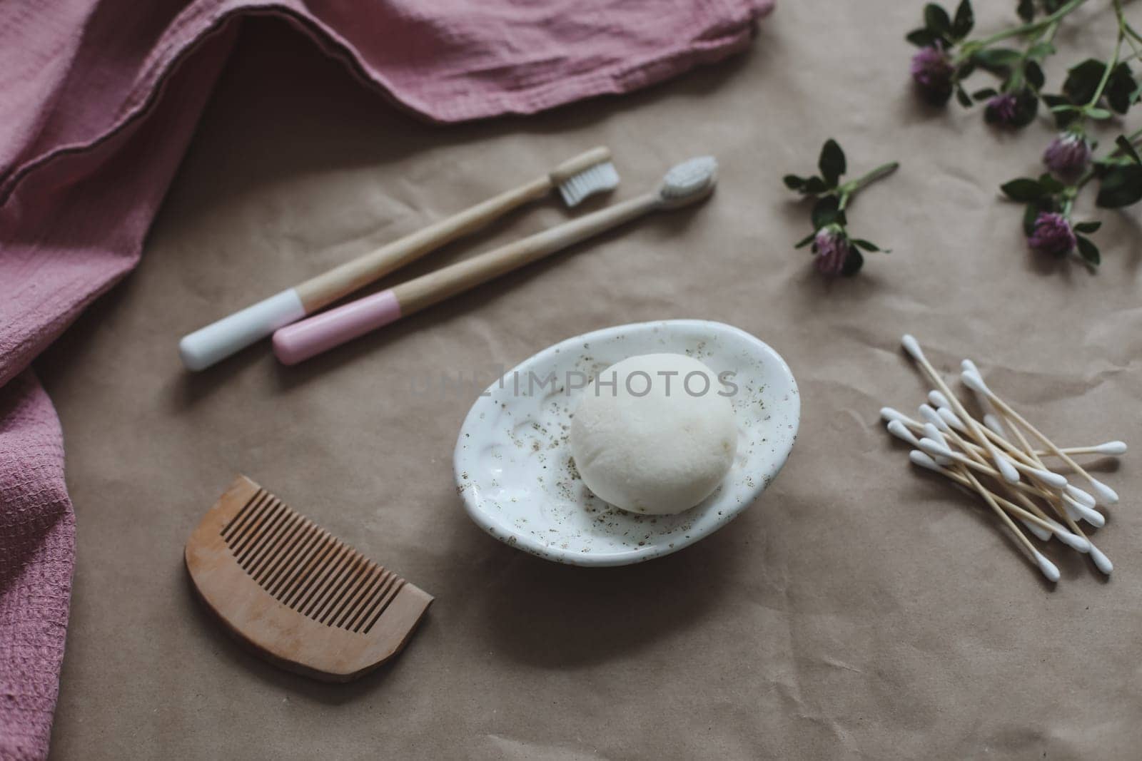 Soap bar or solid shampoo on a soap dish, bamboo toothbrush and towel top view with copyspace. Accessories for personal hygiene. Plastic free and eco friendly products in household by paralisart
