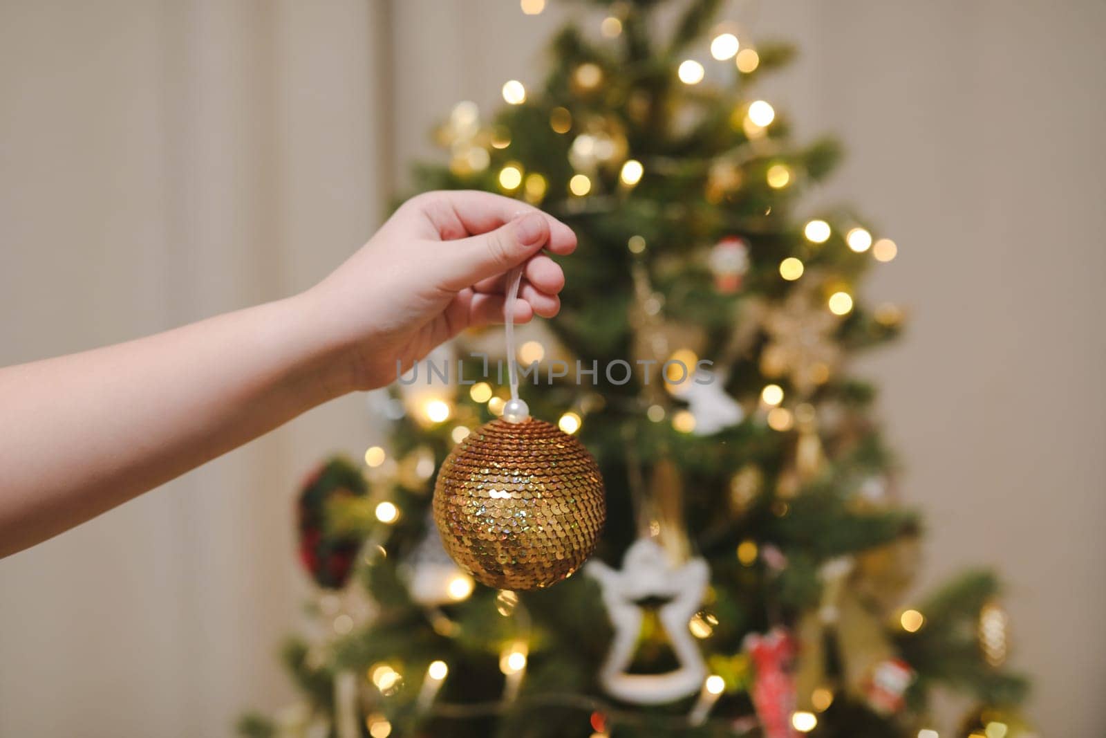 Decorating Christmas tree, holding Christmas toy in a hand. Holiday, Christmas and New Year family celebration concept by paralisart