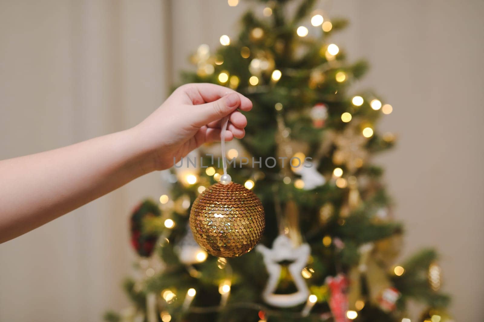 Decorating Christmas tree, holding Christmas toy in a hand. Holiday, Christmas and New Year family celebration concept.