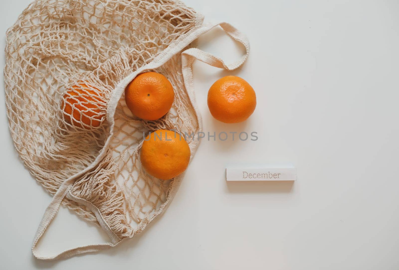 Christmas or New Year composition with fresh tangerines in shopping bag and word December by paralisart