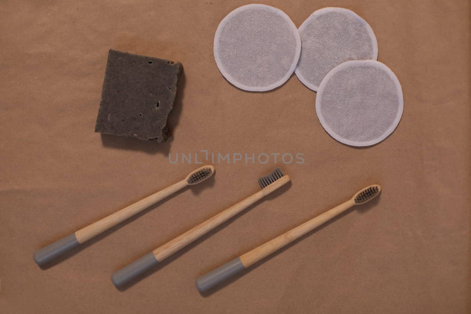 plastic free and eco friendly products in household, wooden toothbrushes, cotton swabs on craft paper background top view by paralisart
