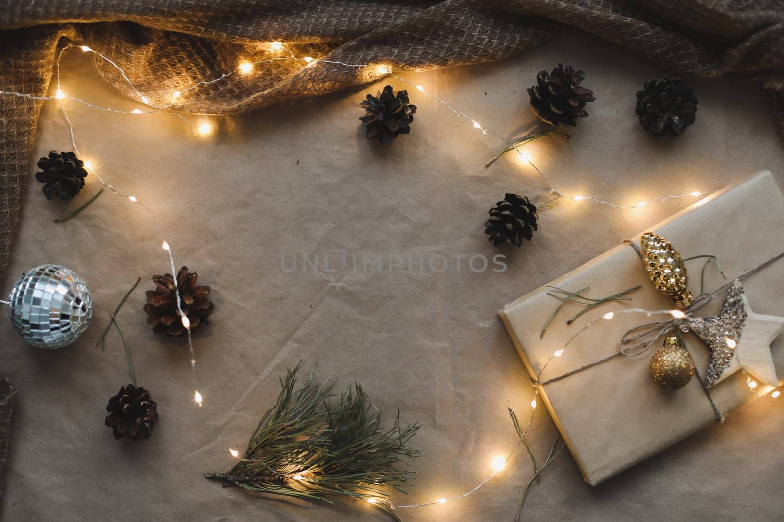 Christmas composition. Gift, fir tree branches, balls on craft paper background. Christmas, winter, new year concept. Flat lay, top view, copy space.