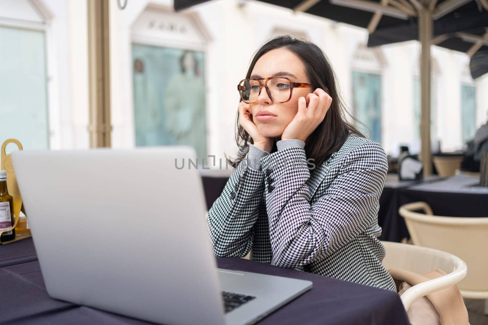 Bored inefficient woman office employee using laptop sitting at restaurant by andreonegin