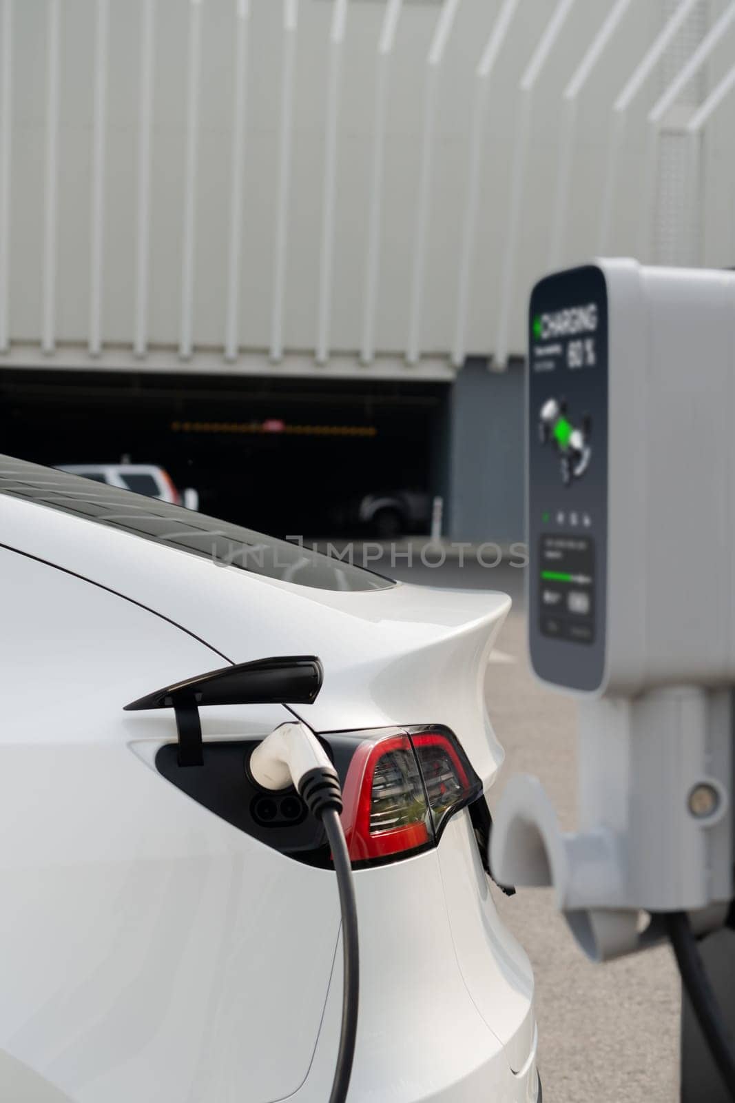 EV electric car recharge battery at parking lot in city commercial zone or mall. Alternative clean energy technology for rechargeable automobile for sustainable and eco friendly travel. Expedient