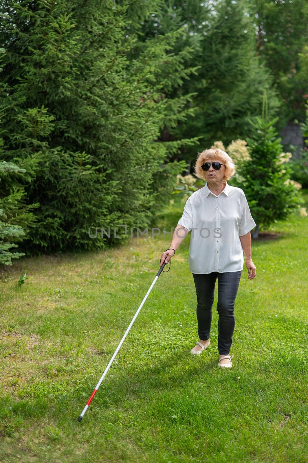 Elderly blind woman walking in the park