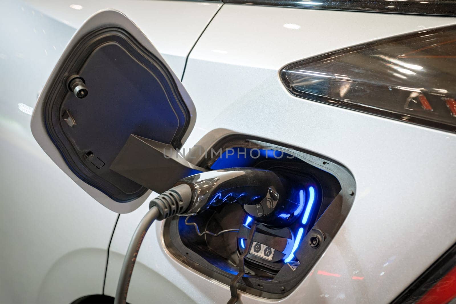 Charging port socket plug in modern electric vehicle EV car close up with charging cable. Environment ecology alternative green renewable clean sustainable energy zero emission concept.