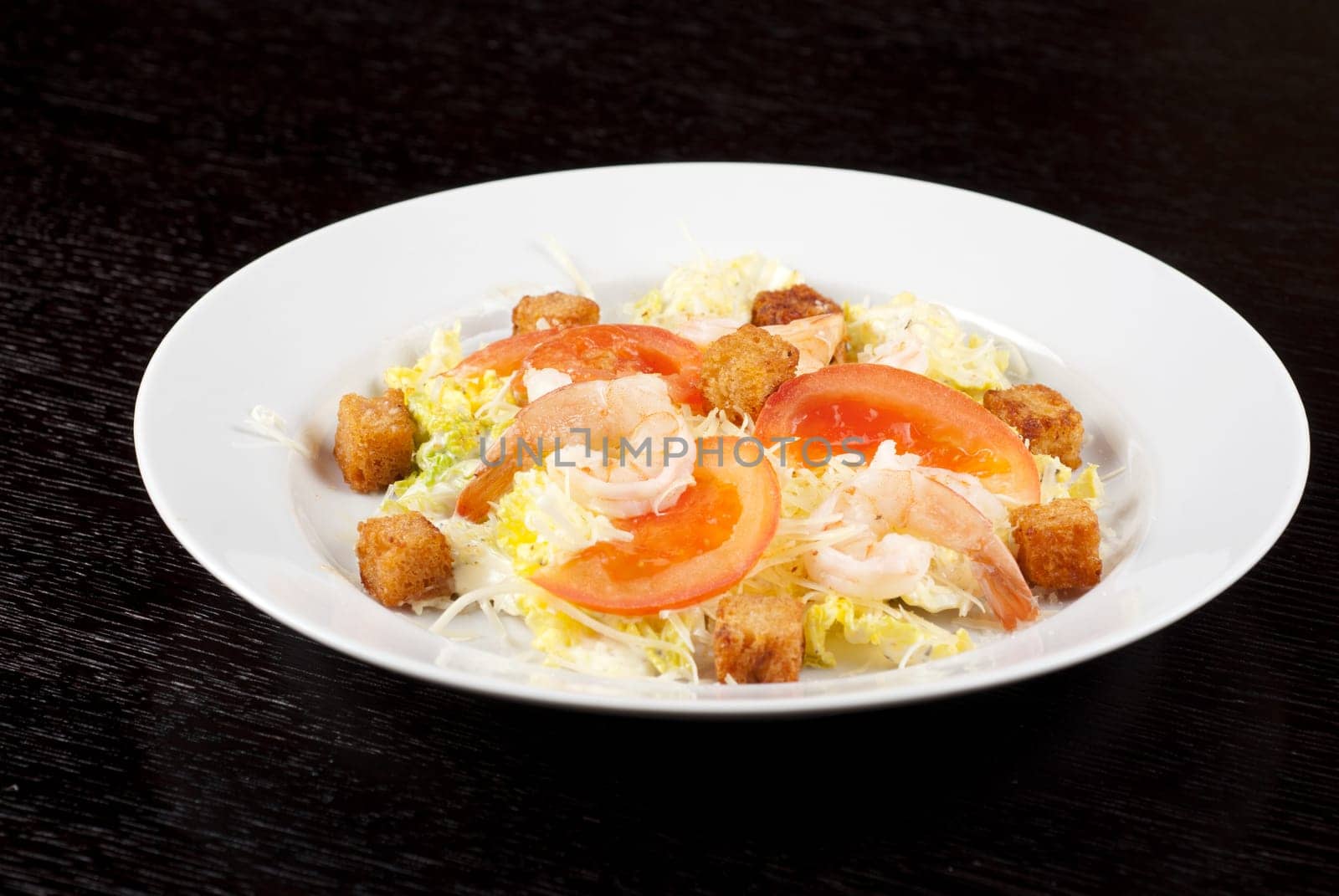 Salad of tiger shrimps, lettuce, chinese cabbage, tomato, garlic rusk, parmesan cheese and sauce