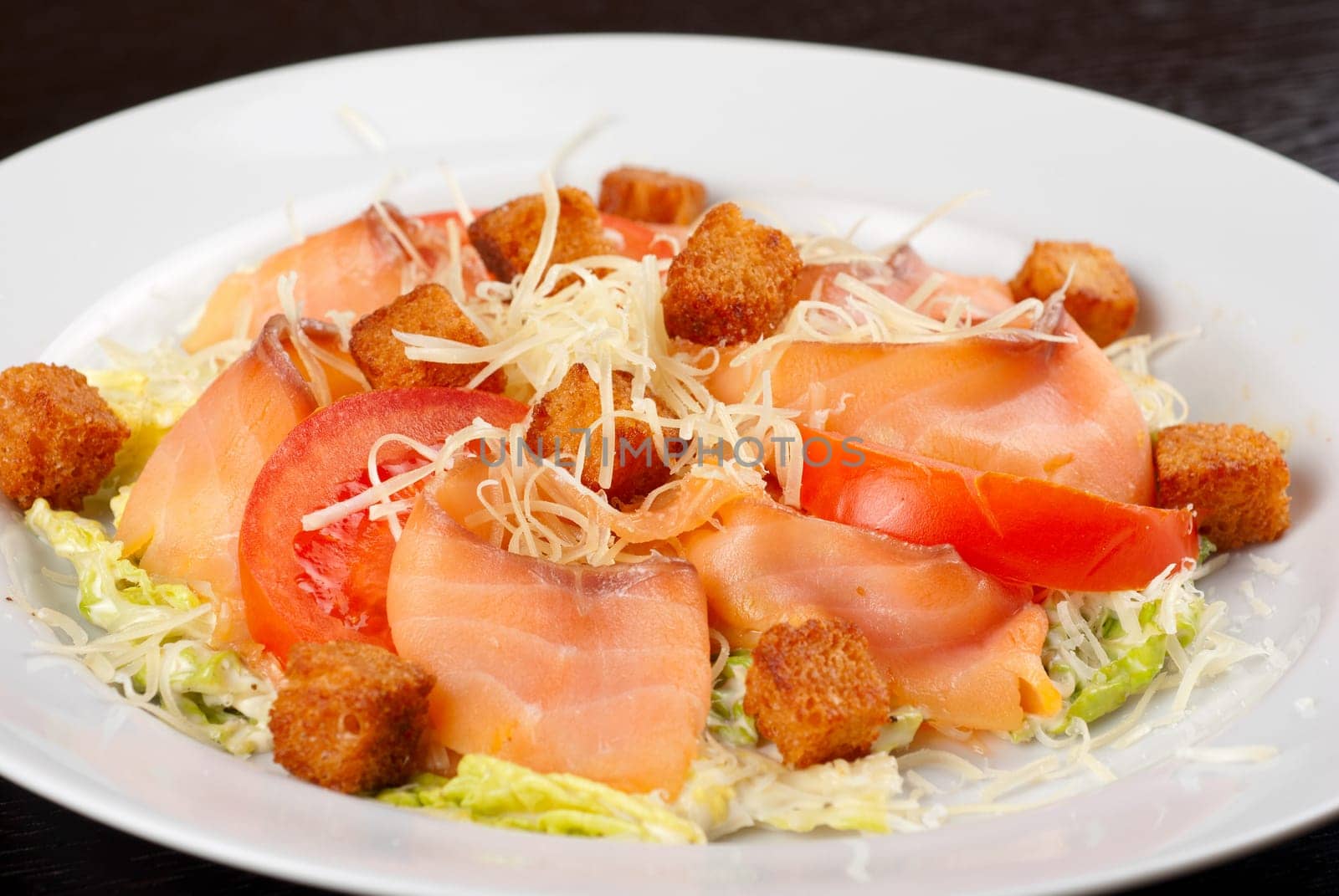 Salad of lettuce, chinese cabbage, tomato, garlic rusk, parmesan cheese, sauce and smoked salmon filet