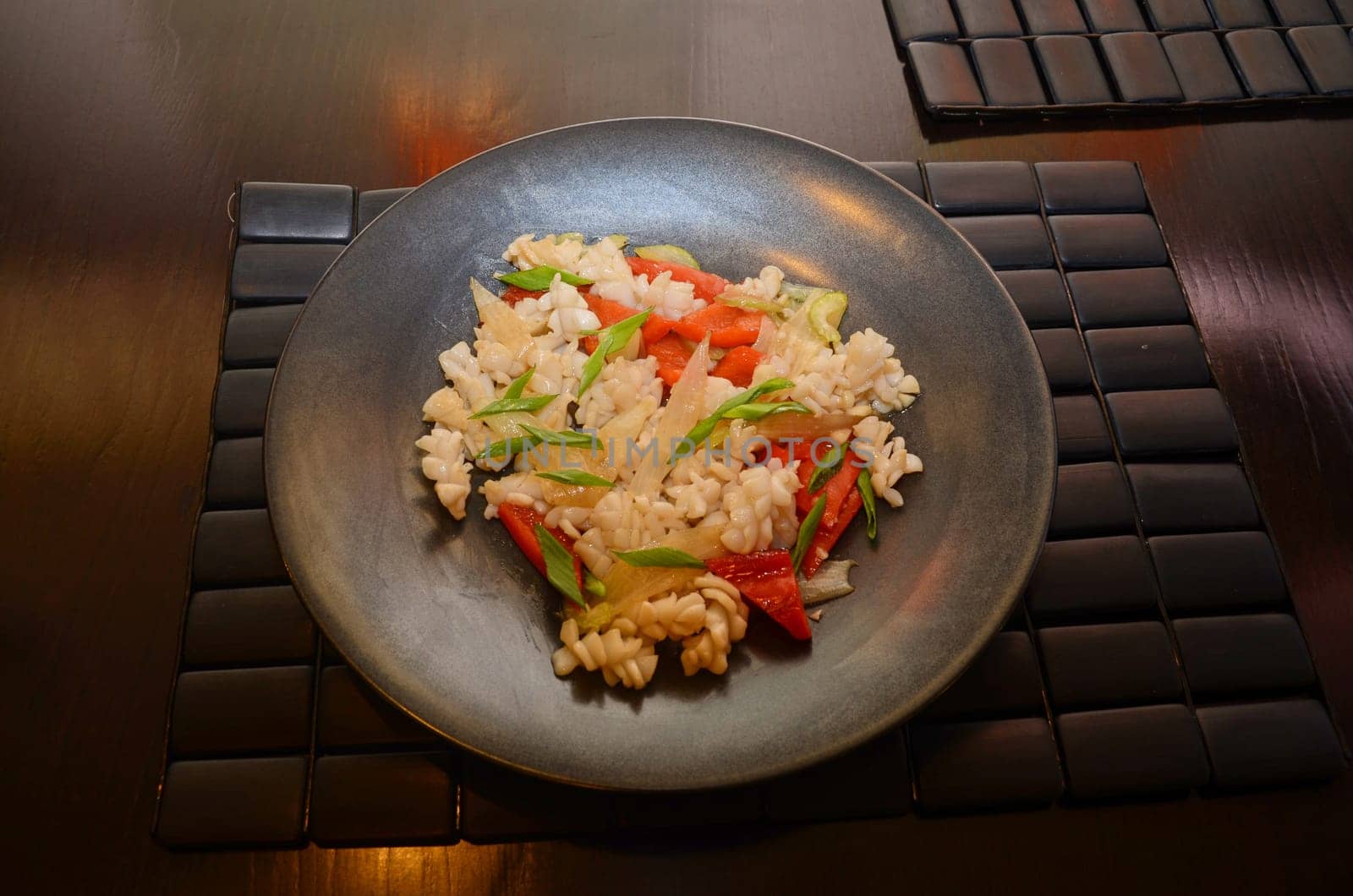 closeup dish of calamari with celery at black plate