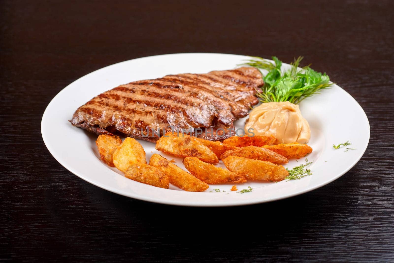 Juicy beef steak stuffed with beef tongue and cheese served with potatoes, greenery and sauce