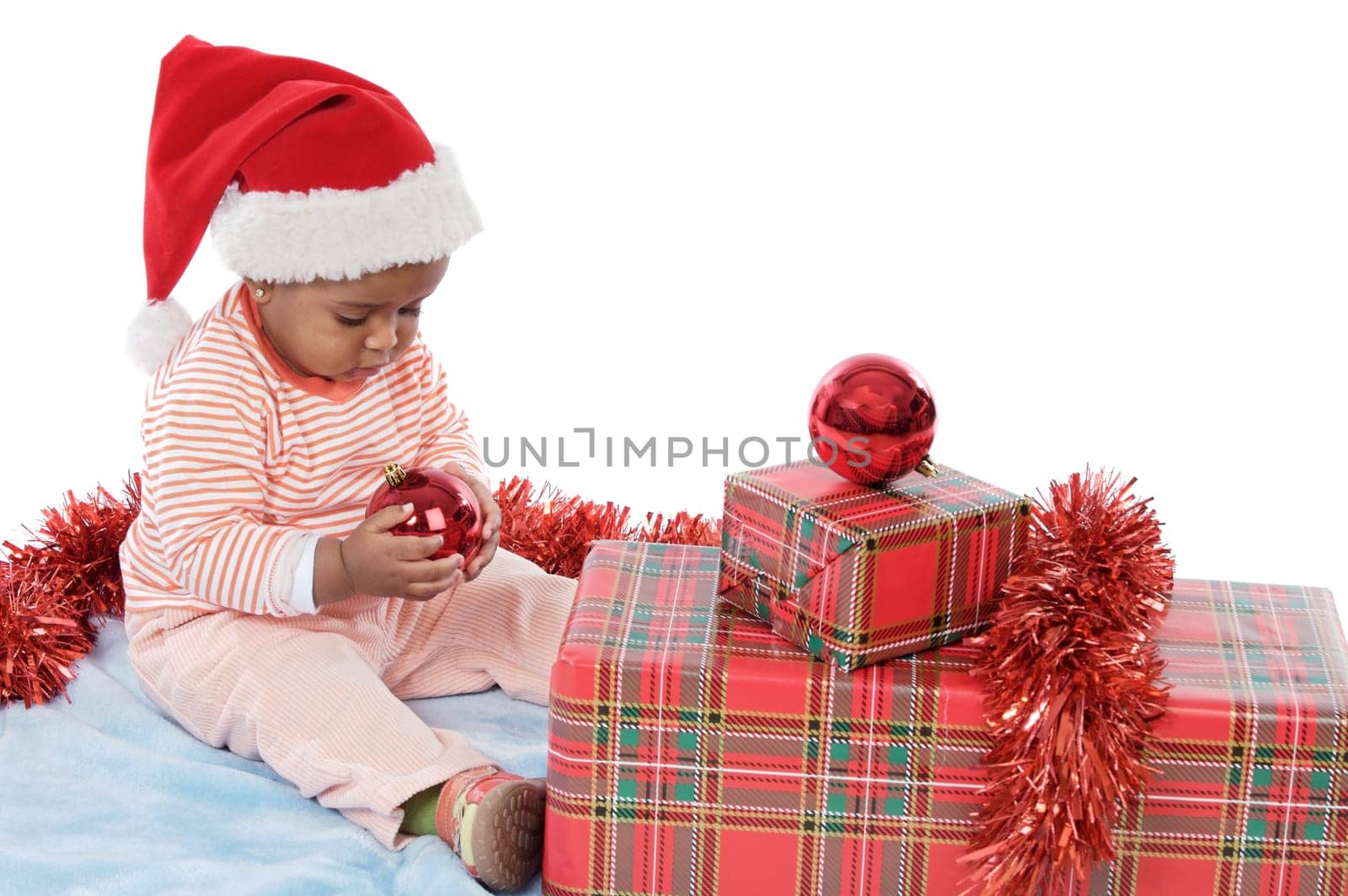 Adorable baby girl with christmas presents and santa hat