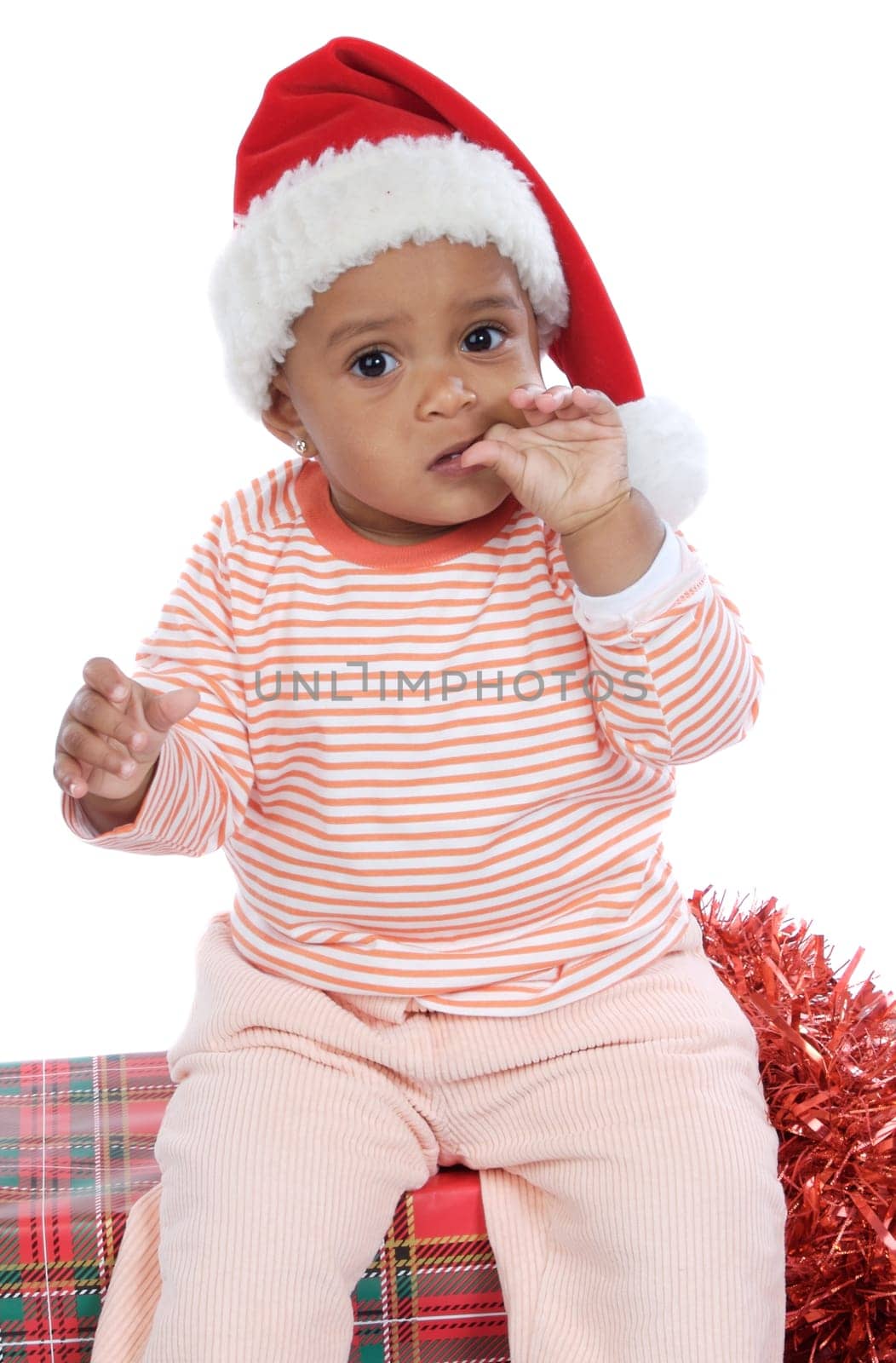 Adorable baby girl seated on christmas presents