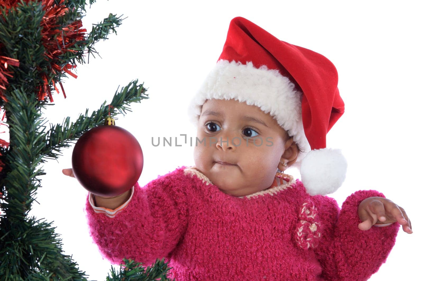 Adorable baby girl playing with christmas tree over white background