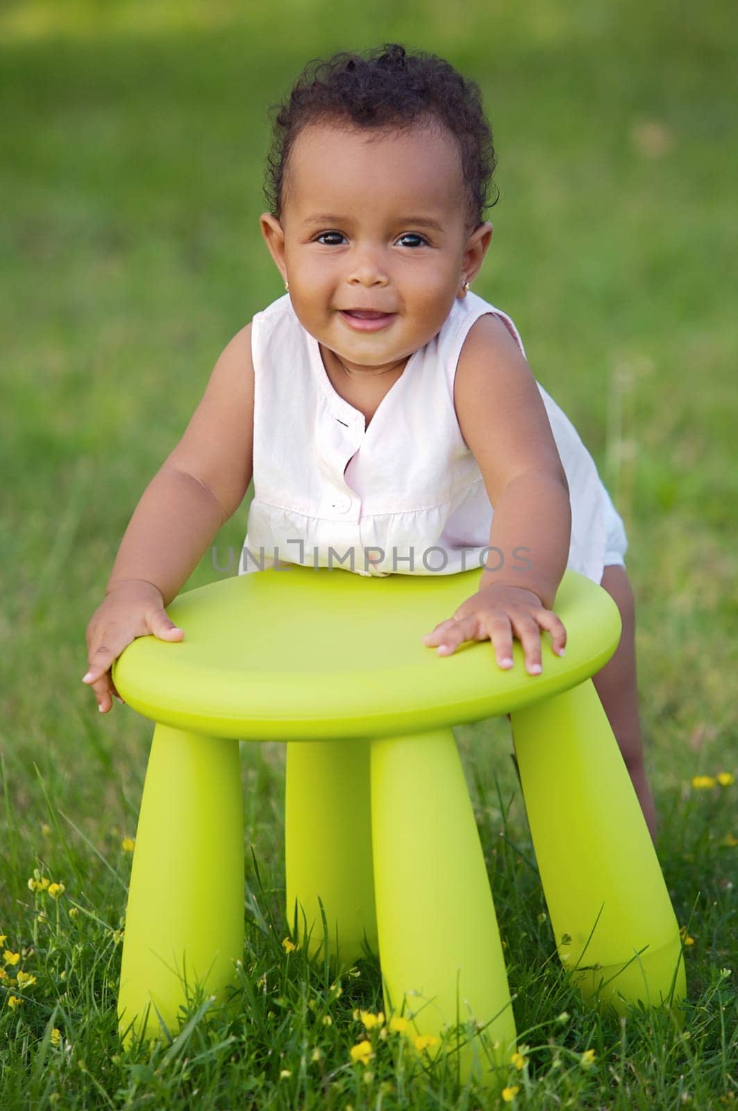 Adorable toddler playing with a chair in the garden