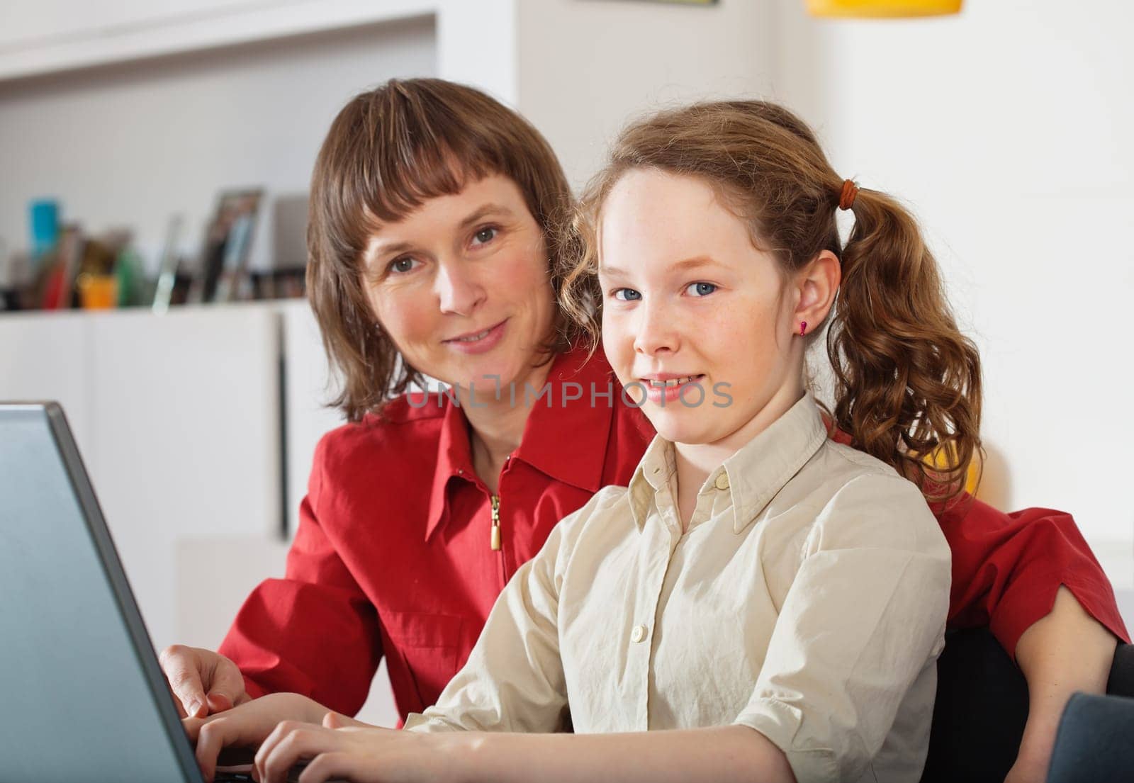 Portrait of mother and teenager girl with laptop computer  at home
