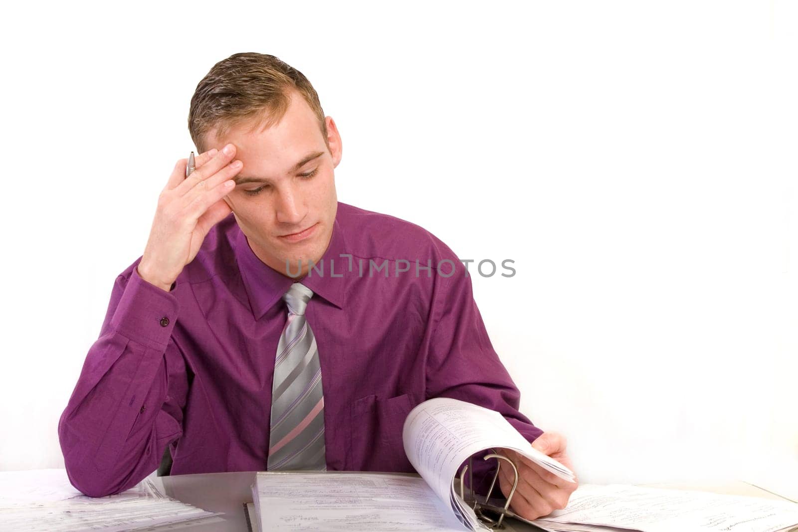 Businessman in office at desk thinking. He looks anxiously at a file folder.