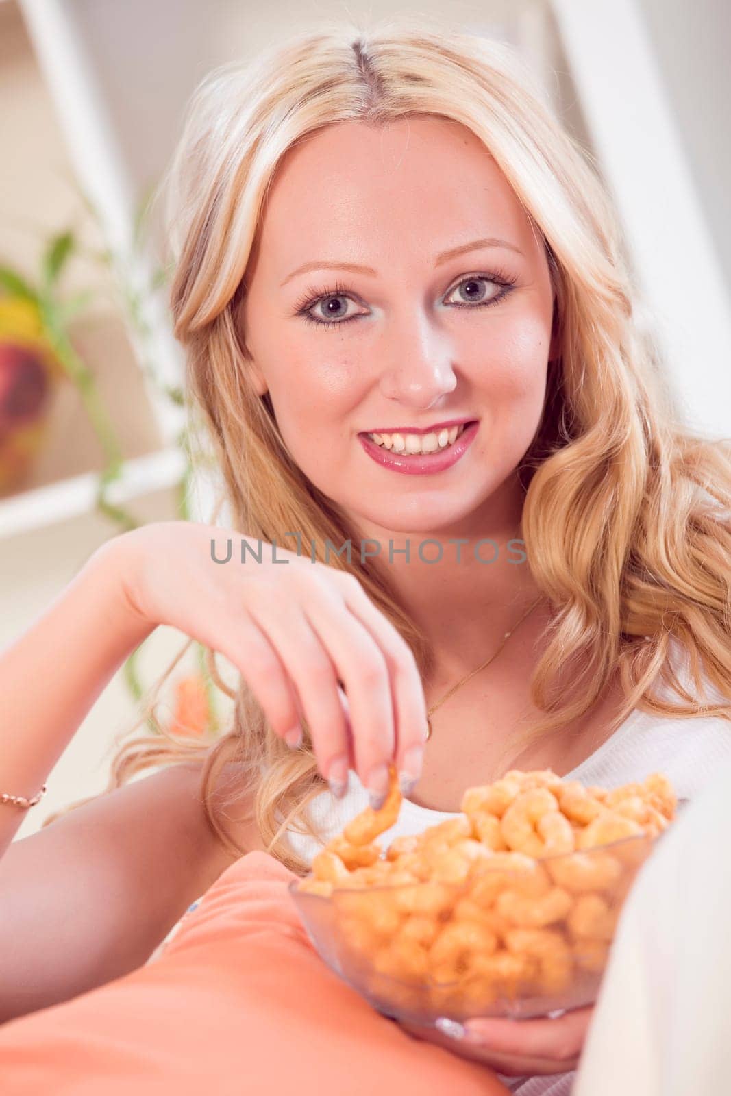 relaxing woman eating chips while sitting on sofa