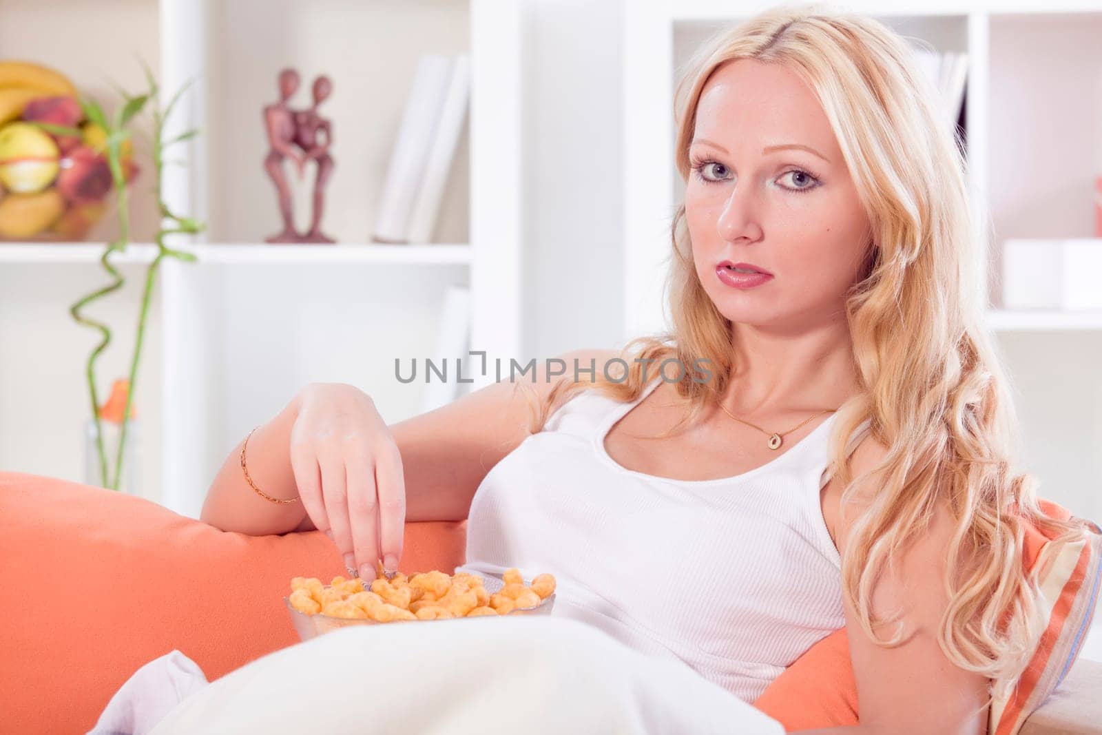 relaxed woman sitting on sofa with unhealthy snack