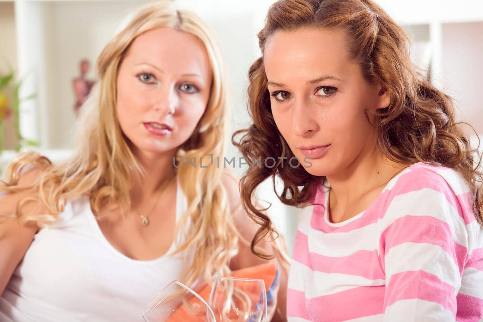 two women friends sitting relaxed on sofa at home