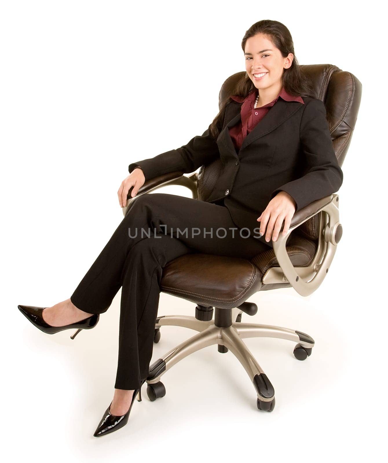 A smiling businesswoman is sitting on a leather chair.