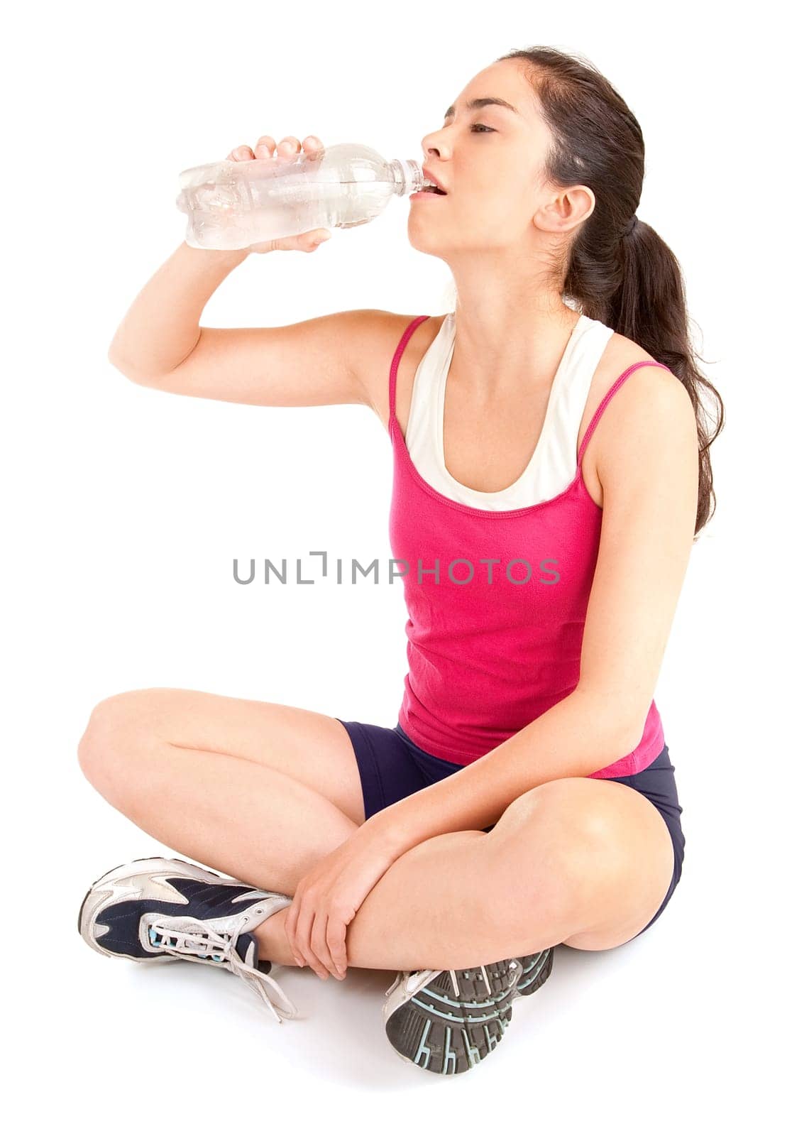 A woman is drinking water from a bottle after a workout.
